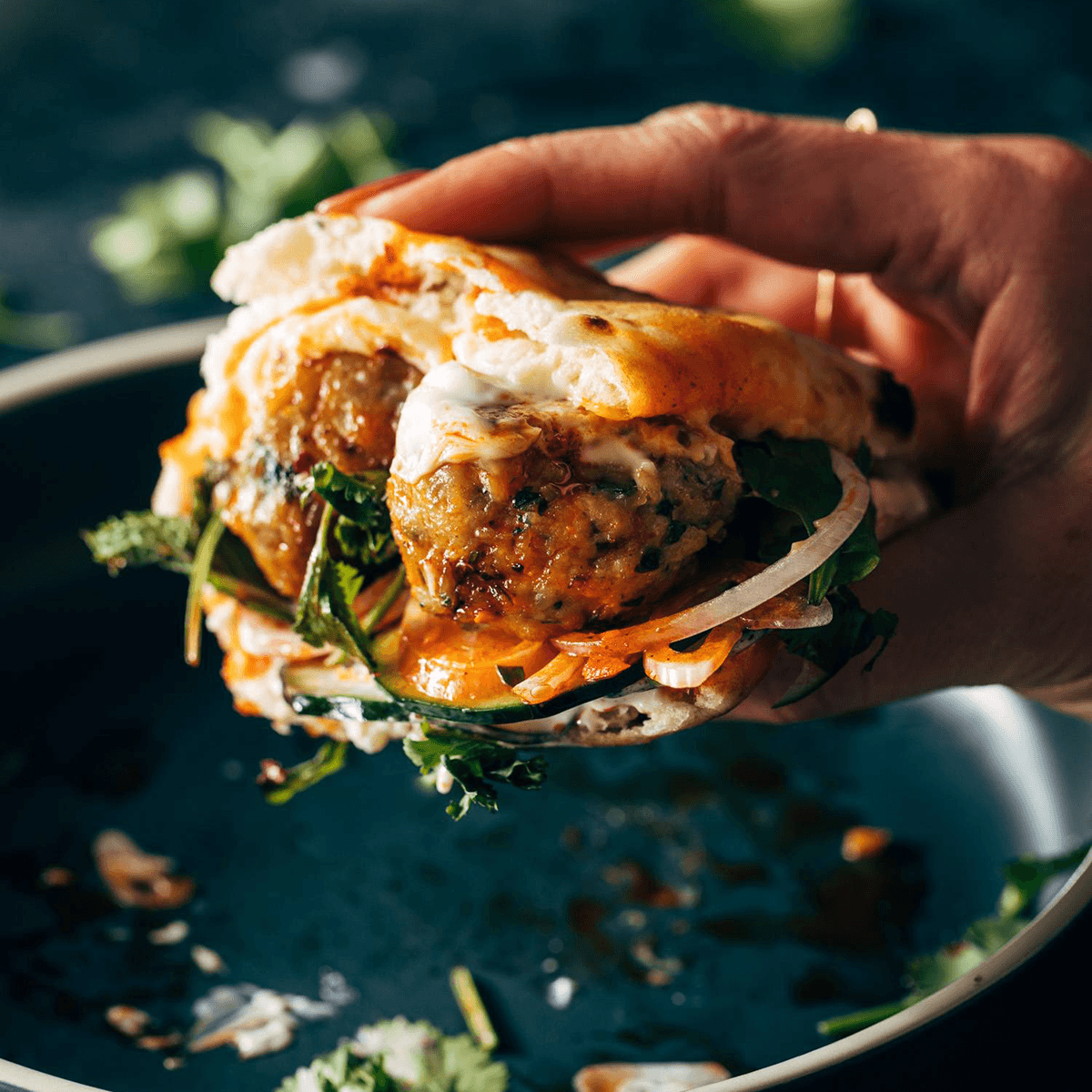 Hand holding a ginger chicken meatball sandwich.