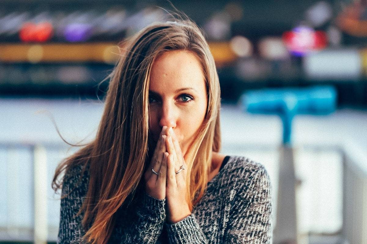 girl looking at camera with hands covering her mouth